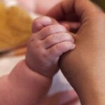 A close up of a person holding a baby's hand